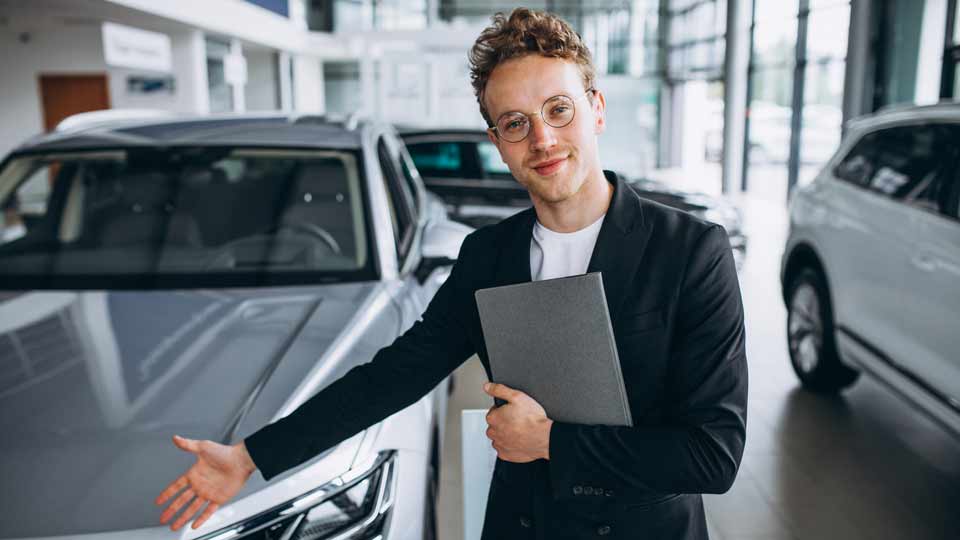 Ein Verkäufer zeigt auf ein Auto und erklärt dem Kunden die Konditionen beim Auto verkaufen Karlsruhe